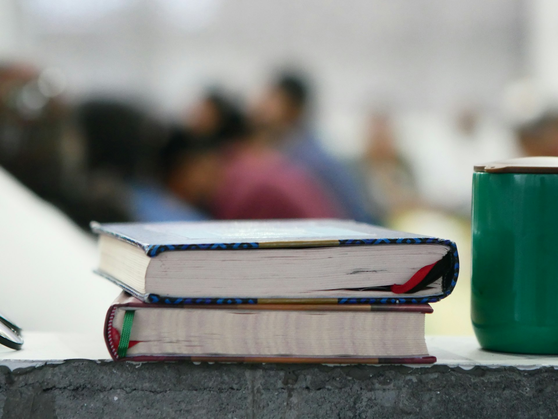 a stack of books sitting next to a green coffee mug